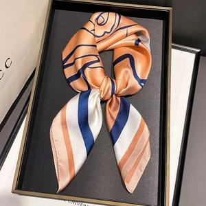Dettaglio di un foulard in raso effetto seta con motivi floreali arancio e righe blu