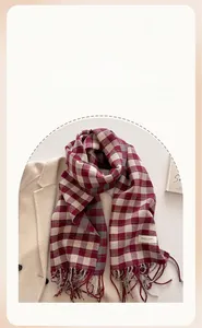 Detail of classic plaid scarf with fringe and elegant label on beige coat