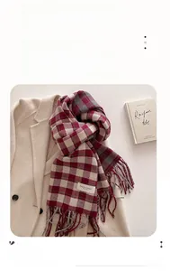 Close-up of thick checkered scarf with tassel details on a beige wool coat