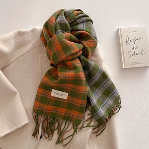 Detail of plaid cashmere scarf with tassels on white wool coat in a cozy winter setting