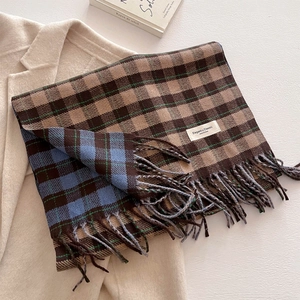 Detail of dual-sided plaid scarf featuring long tassels and Elegant & Classic label