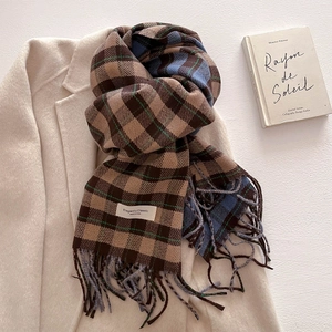 Detail of classic plaid cashmere scarf with fringes on a beige wool coat with book