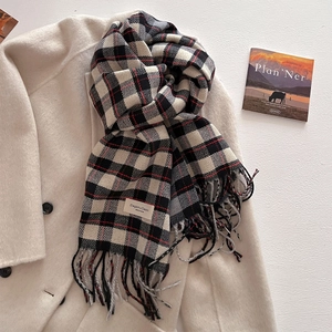 Detail of plaid scarf with thick tassels and elegant woven tag on a beige wool coat
