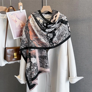 Detail view of abstract printed scarf with fringes over a stylish beige wool coat