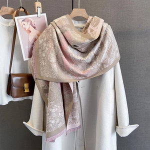 Detail of warm jacquard shawl scarf featuring fringe edges on a beige wool coat