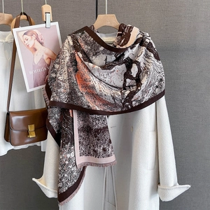 Detail of soft thick scarf featuring brown and orange abstract pattern with fringe edges