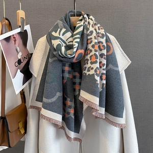 Dettaglio di morbida sciarpa jacquard con stampa leopardata e motivi di foglie verdi