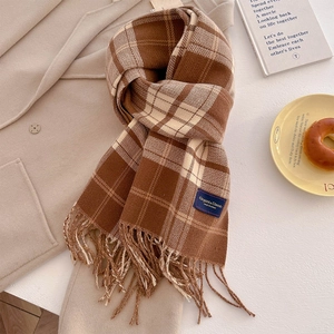 Detailed view of checkered tassel scarf with elegant woven label on warm wool coat