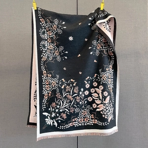 Close-up of floral jacquard patterns on black faux cashmere scarf with fringe