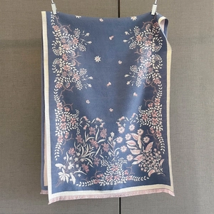 Close-up of botanical floral jacquard pattern and light pink fringes on a navy blue scarf