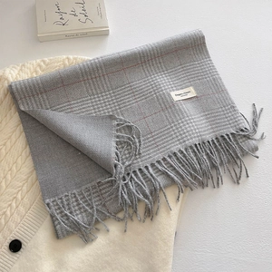 Detailed view of grey plaid scarf texture with soft fringe and elegant woven label