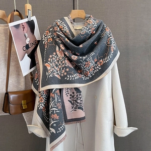 Detail of floral jacquard shawl with short fringe draped over a classic coat