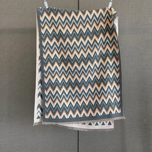 Detail of zigzag knit scarf featuring orange and grey cashmere-feel textured fabric