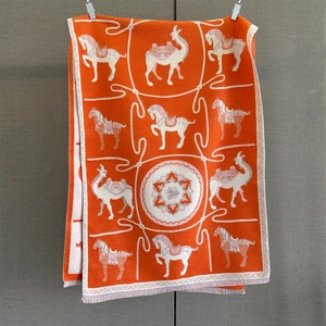 Close-up of orange floral jacquard pashmina with horse patterns and fringe details