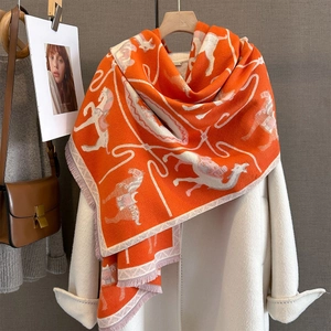 Detail of orange equestrian jacquard knit scarf with horse pattern and soft fringe