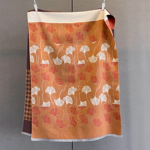 Detail of cashmere-like scarf showing orange ginkgo leaf pattern and dogtooth check reverse