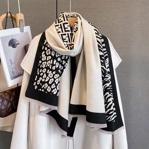 Detail of leopard and zebra pattern patchwork scarf with thick tassels on coat