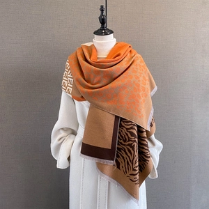 Detail view of thick winter scarf featuring leopard print and orange color block patterns