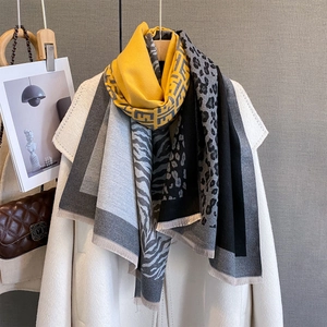 Detail of yellow geometric knit scarf with leopard and zebra print patterns and tassels