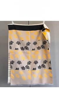 Detail of jacquard scarf with yellow ginkgo leaf pattern and soft tassel edges