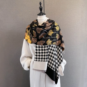 Detail view of winter ginkgo leaf and houndstooth pattern patchwork scarf with tassels