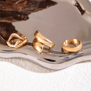 Three-piece gold wave minimalist ring set displayed on a stylish silver mirror tray