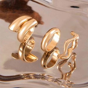 Three-piece gold ring set featuring minimalist bands and irregular wavy designs on metal