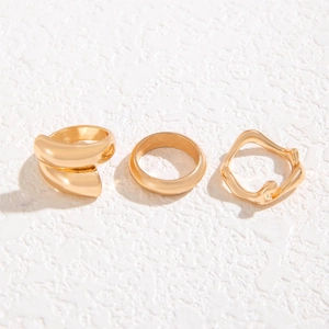 Three-piece minimalist gold ring set featuring wavy, layered, and smooth bands on stone