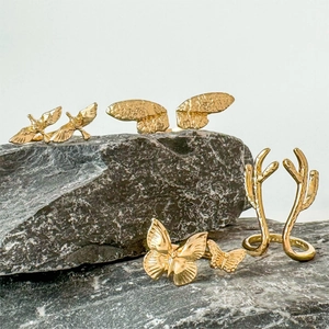 Goldenes Ring-Set mit Schmetterling, Geweih und Vogelflügeln auf dunklem Stein