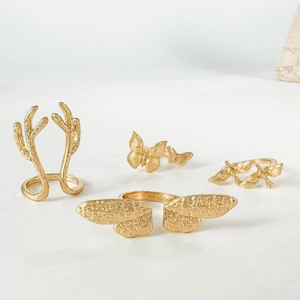 Detailansicht von 4 goldenen Ringen mit Schmetterlings- und Geweihmotiven mit Textur