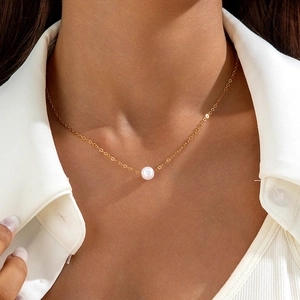 Nahaufnahme einer minimalistischen Goldkette mit einer einzelnen weißen Perle am Modell