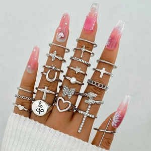 Detail of silver vintage ring set featuring butterfly, snake, and pearl motifs on hand