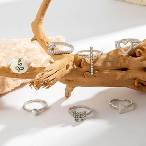 Detail of 7-piece vintage silver ring set with snake, butterfly, and pearl on wooden decor