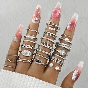 Close-up of vintage silver ring set featuring butterfly, moon, and pearl details on fingers