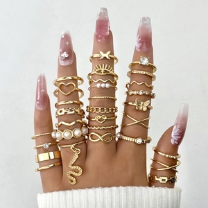 Close-up of bohemian gold ring set featuring butterfly, snake, and pearl motifs