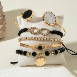 Detail of 5-piece gold bracelet set with shell, evil eye and infinity charms on velvet