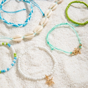 Close-up of bohemian beach jewelry set with sea shells, starfish and turtle charms on sand