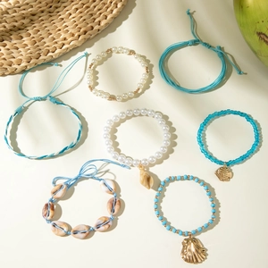 Detail of seven Bohemian beach bracelets with shells, pearls and blue starfish charms