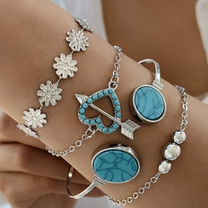 Detail of bohemian silver bangles set featuring turquoise stones and daisy floral charms