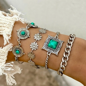 Close-up of bohemian four-piece bracelet set with turquoise stones and leaf floral charms