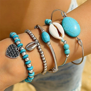 Detail of bohemian layered bracelets with turquoise stones, shell pendant and love engraving