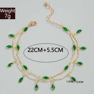 Macro view of gold layered anklet featuring green leaf pendant and dimension markings