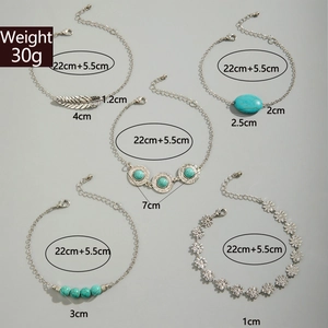 Close-up of five-piece silver turquoise anklet set with feather and floral charms