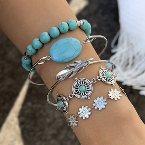 Detail of bohemian five-piece bracelet set with turquoise stones and feather motifs