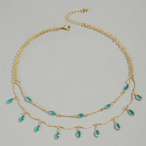 Detail of double-layer gold necklace with marquise blue stones and drop fringe