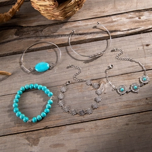 Close-up of five bohemian turquoise bracelets with sunflower and leaf details on wood
