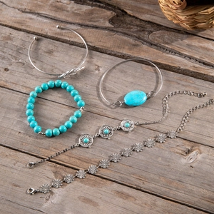 Close-up of Bohemian 5-piece bracelet set with turquoise beads and leaf motifs on wood