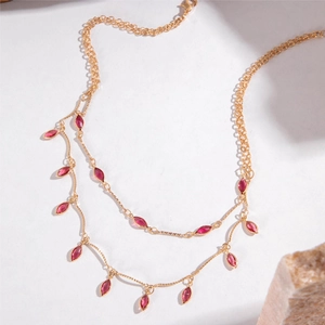 Double-layer gold necklace with red marquise rhinestone tassels on white background