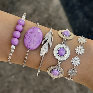 Detail of bohemian five-piece bracelet set featuring turquoise leaf and feather charms