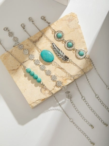 Detail of bohemian silver bracelets with turquoise beads and feather charms on stone
